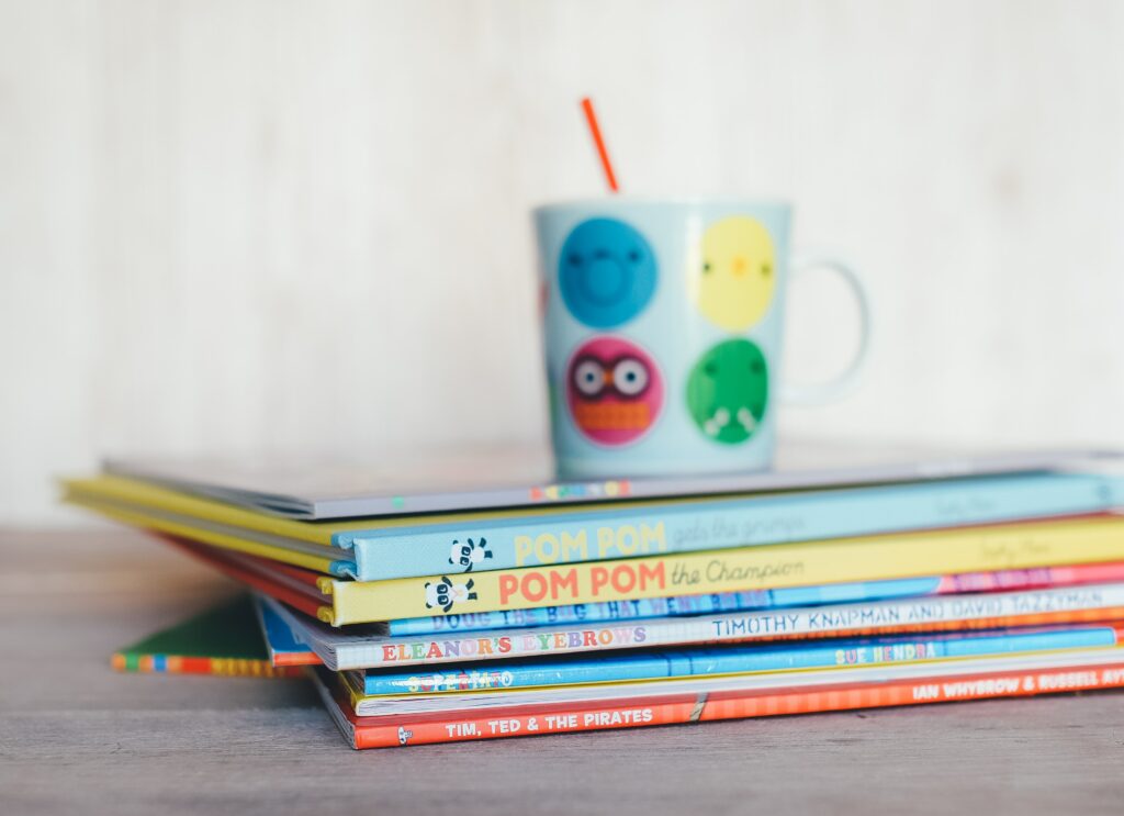 Pile of children's books with mug on top