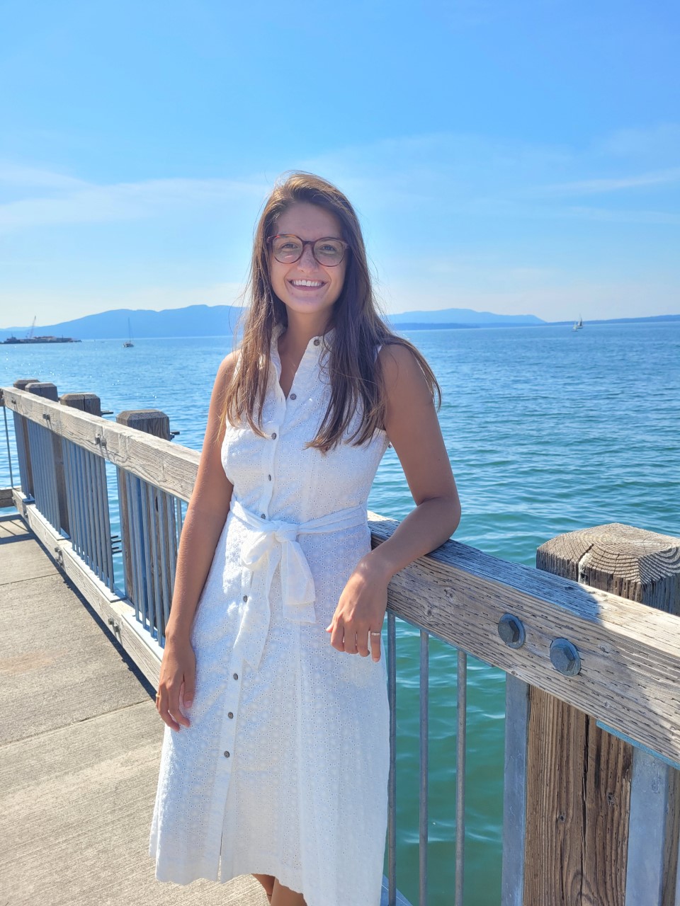 Ali Kubeny leaning on a pier railing, a large body of water in the background